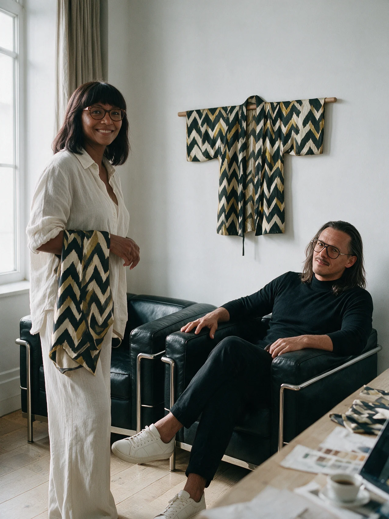 Alberto Maccari and designer Aïssata in the KIMOWI studio, holding a printed silk sample, the kimono on its rail behind them